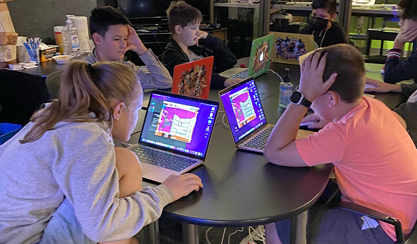 students around table looking using laptop